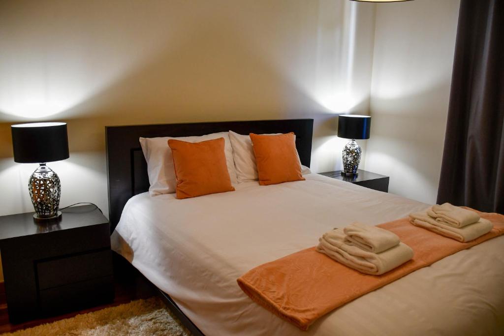 - une chambre dotée d'un lit avec 2 lampes et des serviettes dans l'établissement Tranquility Apartment, à Caniço
