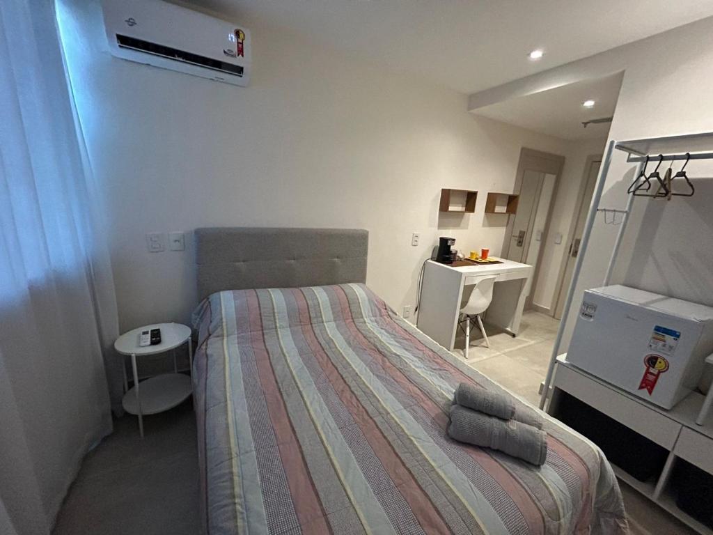 Habitación pequeña con cama y escritorio. en Flat América Campos Pelinca en Campos dos Goytacazes