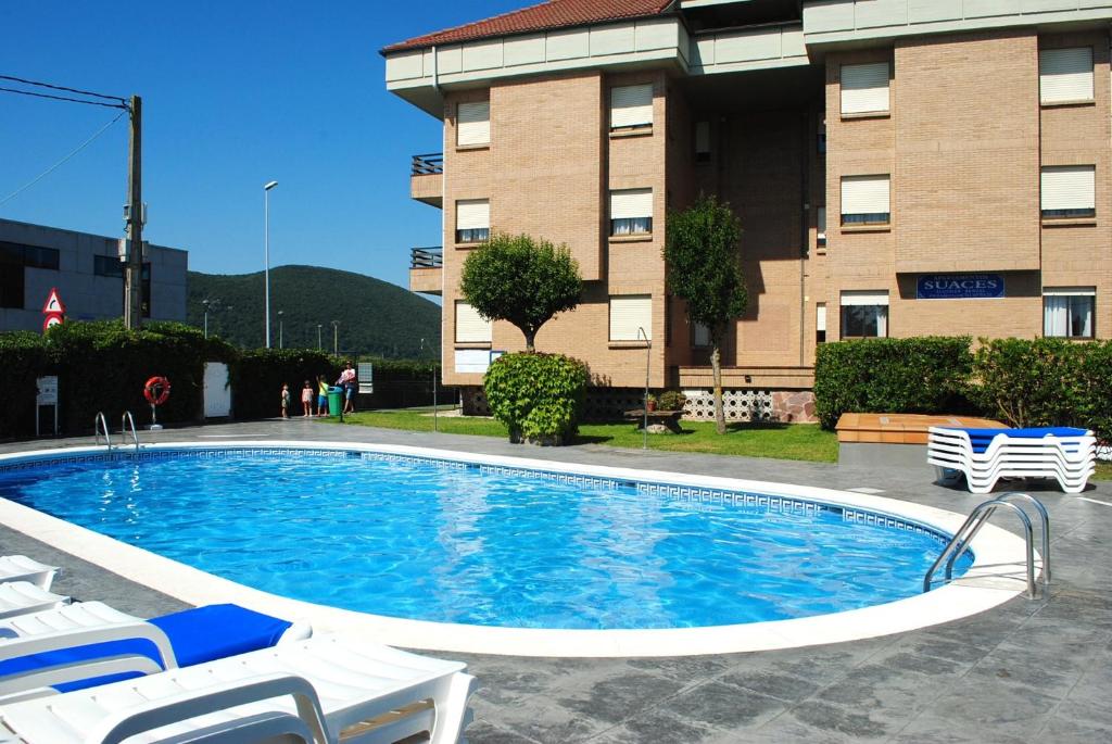 a large swimming pool in front of a building at Apartamentos Suaces in Noja