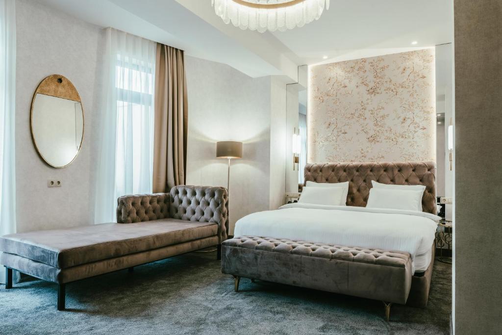 a bedroom with a bed and a couch and a mirror at Highgarden Hotel in Tbilisi City