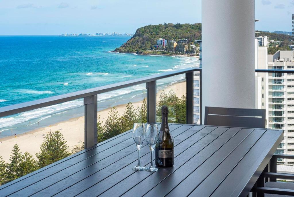 a table with a bottle of wine and two wine glasses at Breathtaking Burleigh Beach Abode in Gold Coast