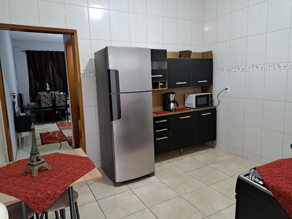 a kitchen with a stainless steel refrigerator and a table at Casa aconchego Parque Mambucaba in Angra dos Reis