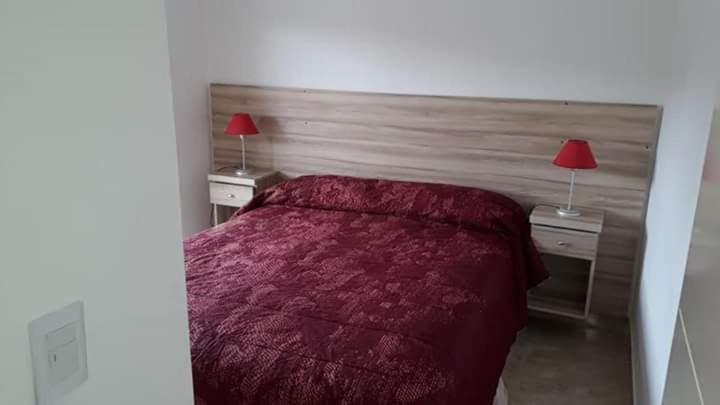 a bedroom with a red bed and two night stands with lamps at depto pinamar in Pinamar