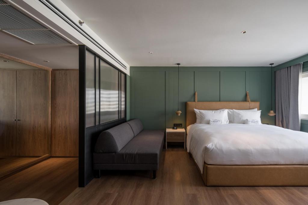 A king bedroom with a sofa, built-in storage and a dark green accent wall.
