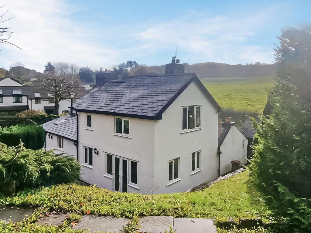 a white house with a black roof at Tir-y-coed in Gwernymynydd