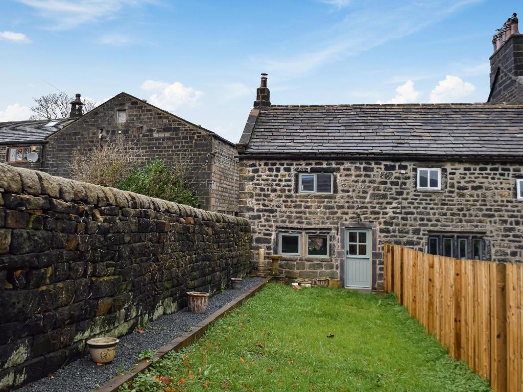a stone house with a stone wall and a yard at Little Jacks Cottage in Todmorden