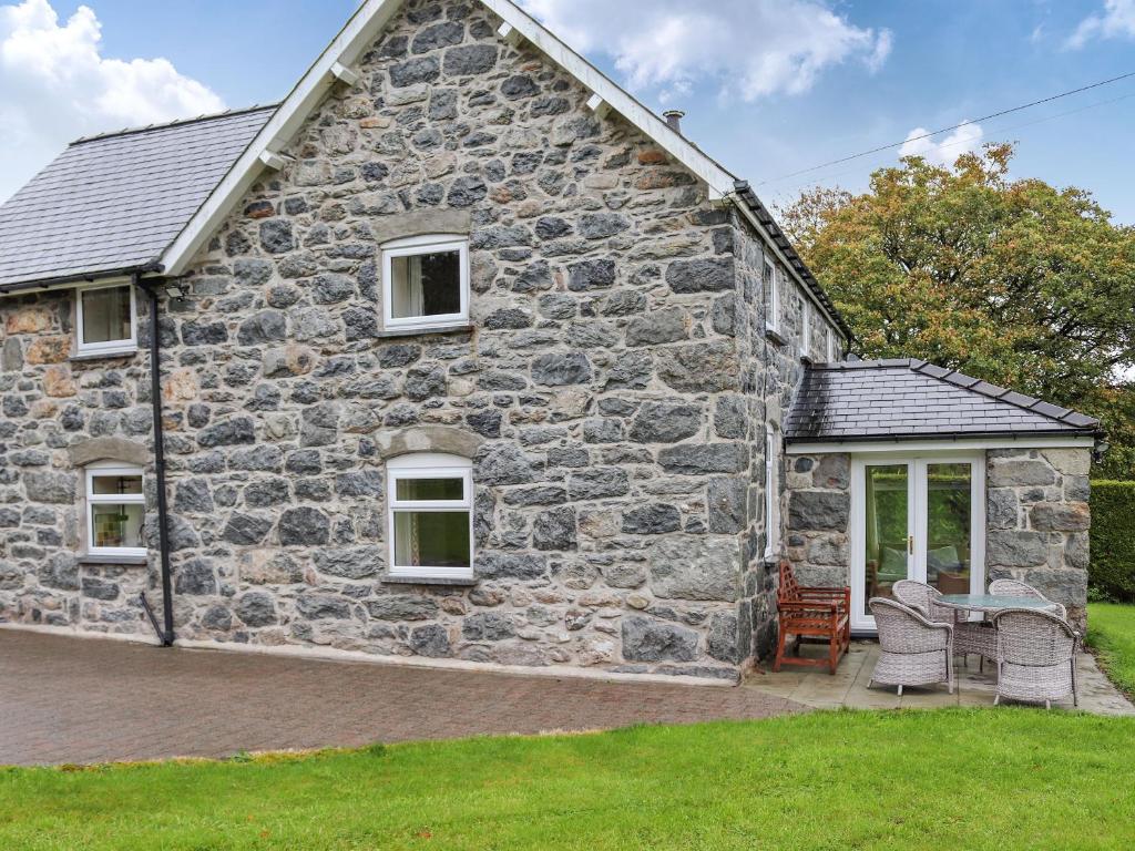 a stone house with a patio in front of it at Plas Madog in Llanuwchllyn