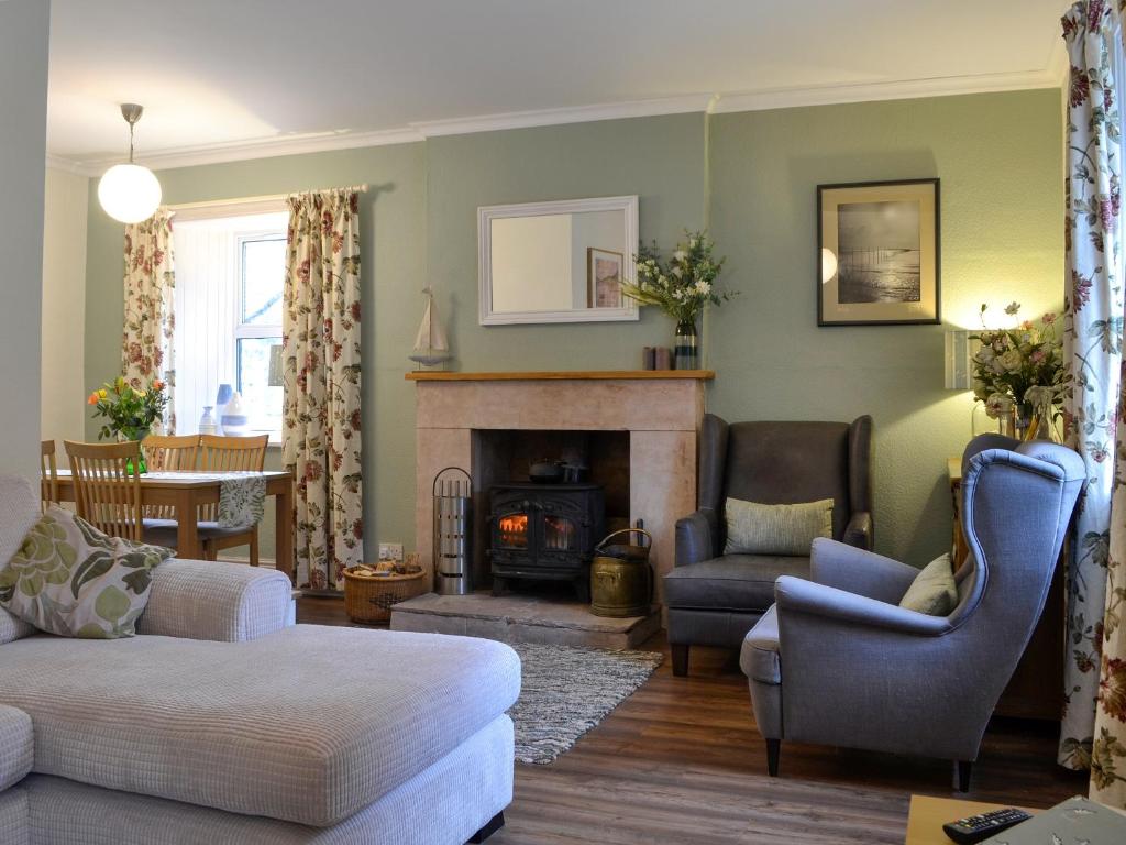 uma sala de estar com um sofá e uma lareira em Clachries Cottage em Boreland of Colvend