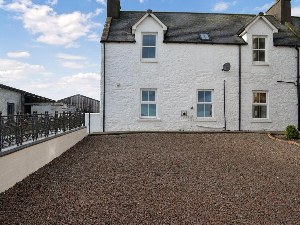a white house with a gravel driveway at The Old Cheese Loft in Colfin