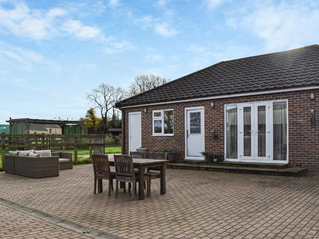 een patio met een tafel en stoelen voor een huis bij Chapel Farm in Stelling