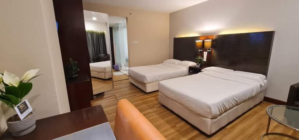 a hotel room with two beds and a desk and a table at BV3 Studio Type with swimming pool in KK City Centre in Kota Kinabalu