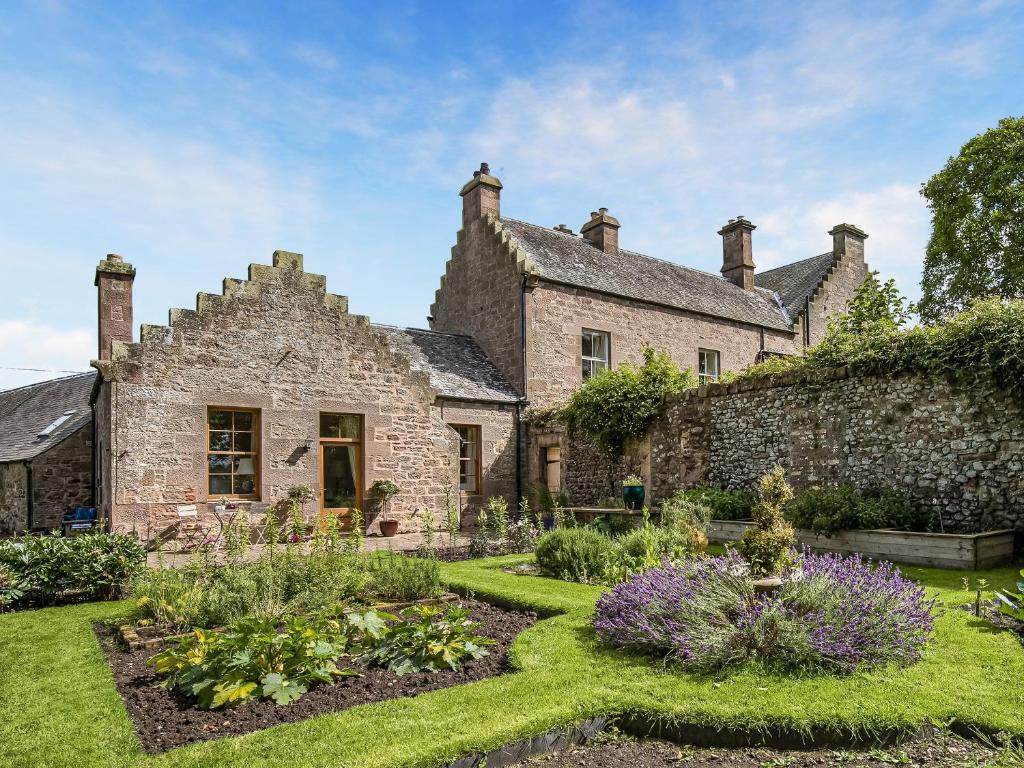 an old stone house with a garden in front of it at Little Swinton - Garden Cottage in Swinton