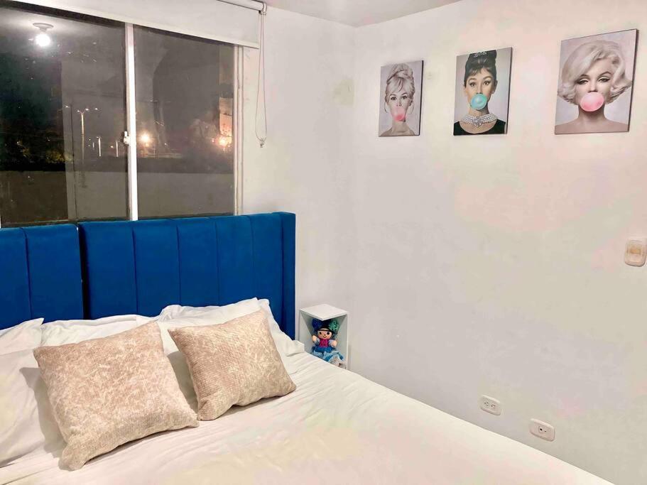 een bed met een blauw hoofdeinde en foto's aan de muur bij Increible apartamento en vup in Valledupar