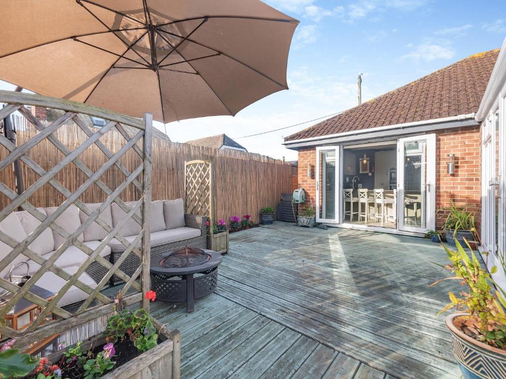 eine Terrasse mit einem Sofa und einem Sonnenschirm in der Unterkunft Anchor Cottage in South Hayling