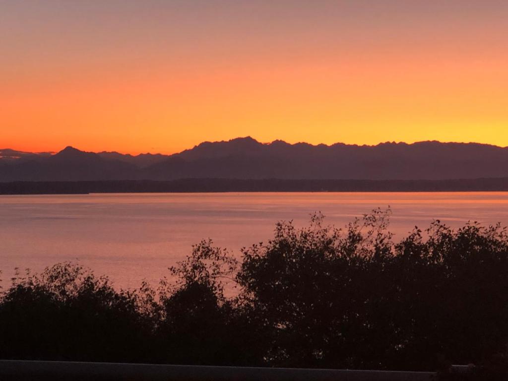 einen Sonnenuntergang über dem Wasser mit Bergen im Hintergrund in der Unterkunft 1-Bedroom Seaview Guesthouse on Seattle Luxury Estate with Views of Olympic Mountains in Seattle