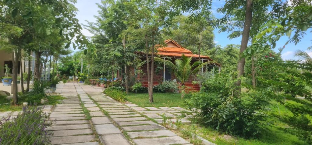 una passerella in un parco con un edificio e alberi di Thiện Homestay One a Ấp Long Lâm