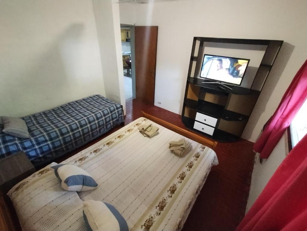 um pequeno quarto com uma cama e uma televisão em Posada La Justy EZEIZA em Ezeiza