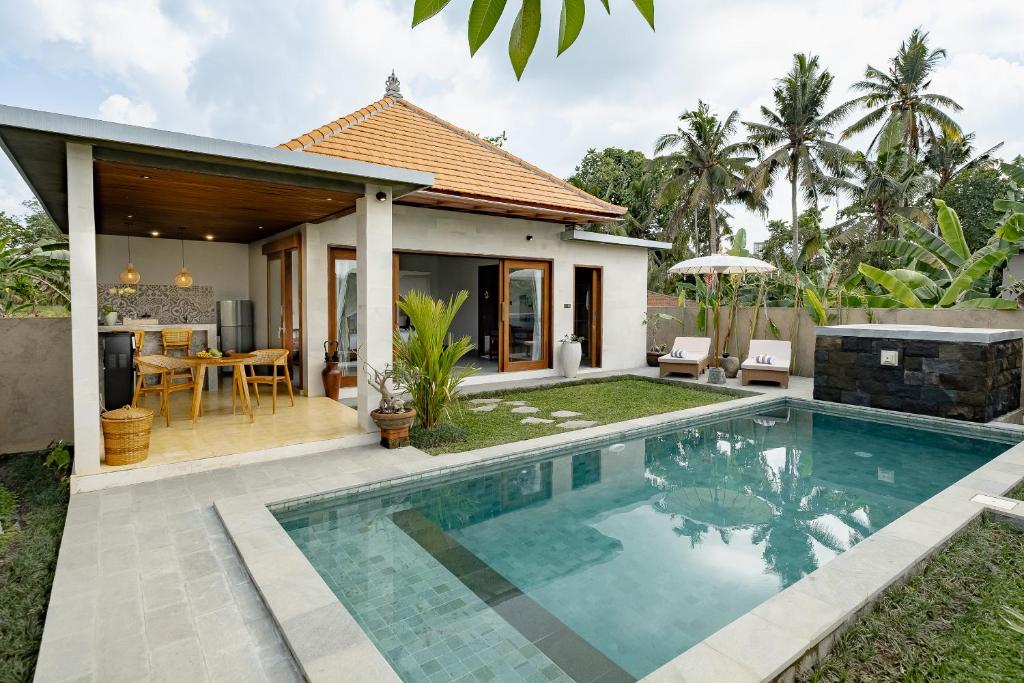 a villa with a swimming pool in front of a house at Suarga Loka Ubud Villa in Ubud