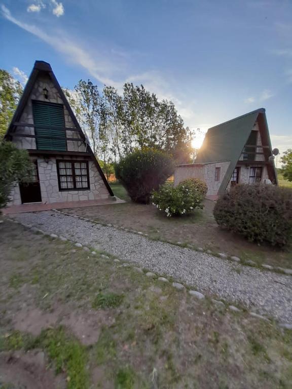 a house with a gambrel roof and a gravel driveway at Cabañas Wencesmar in Hipólito Yrigoyen