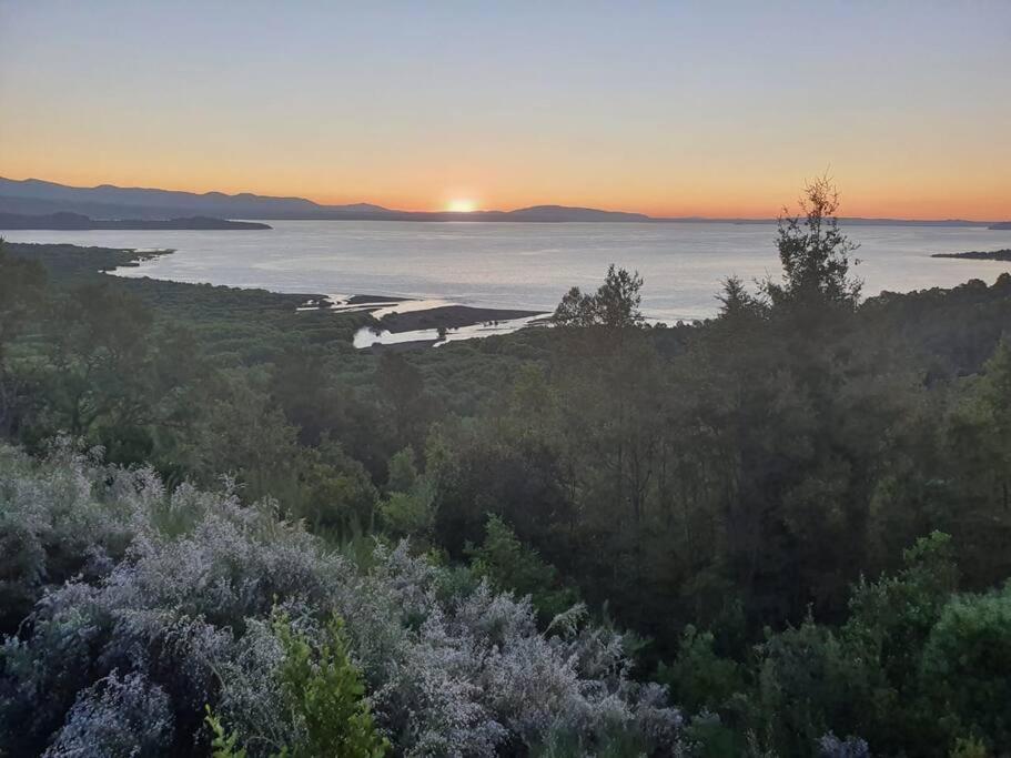 una puesta de sol sobre un cuerpo de agua con árboles en Pucón, Espectacular Casa en Pucón