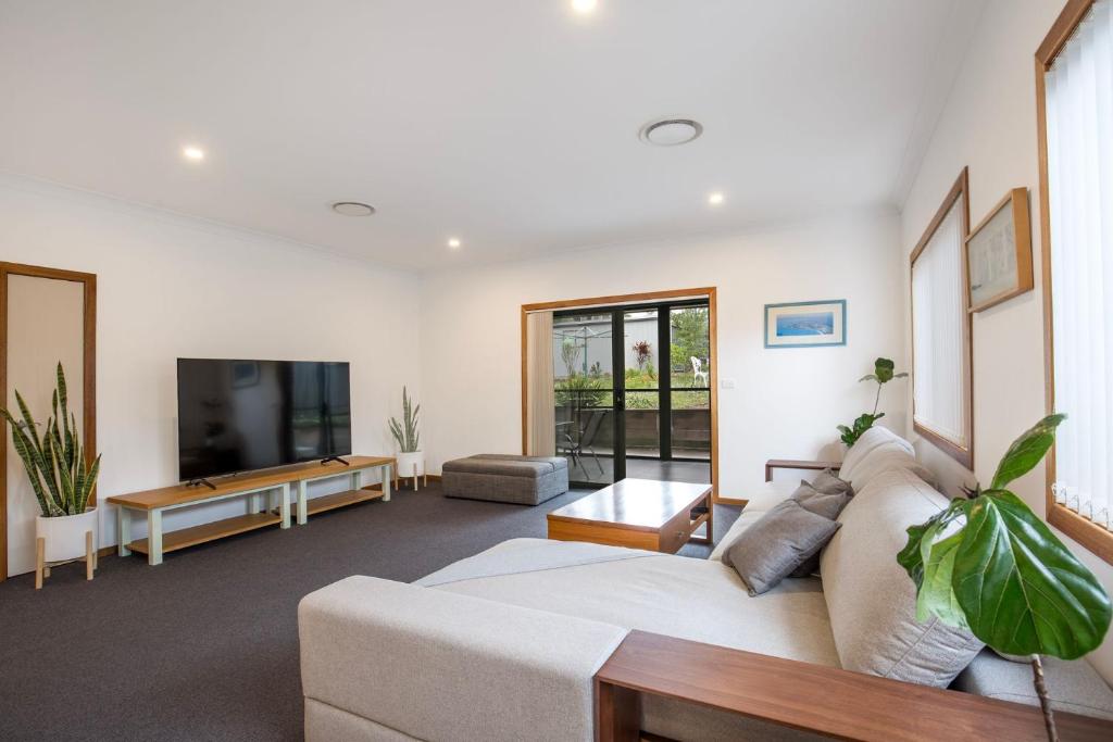 a living room with a couch and a tv at Tangerine - Pet Friendly - 3 Mins Walk to Beach in Sanctuary Point