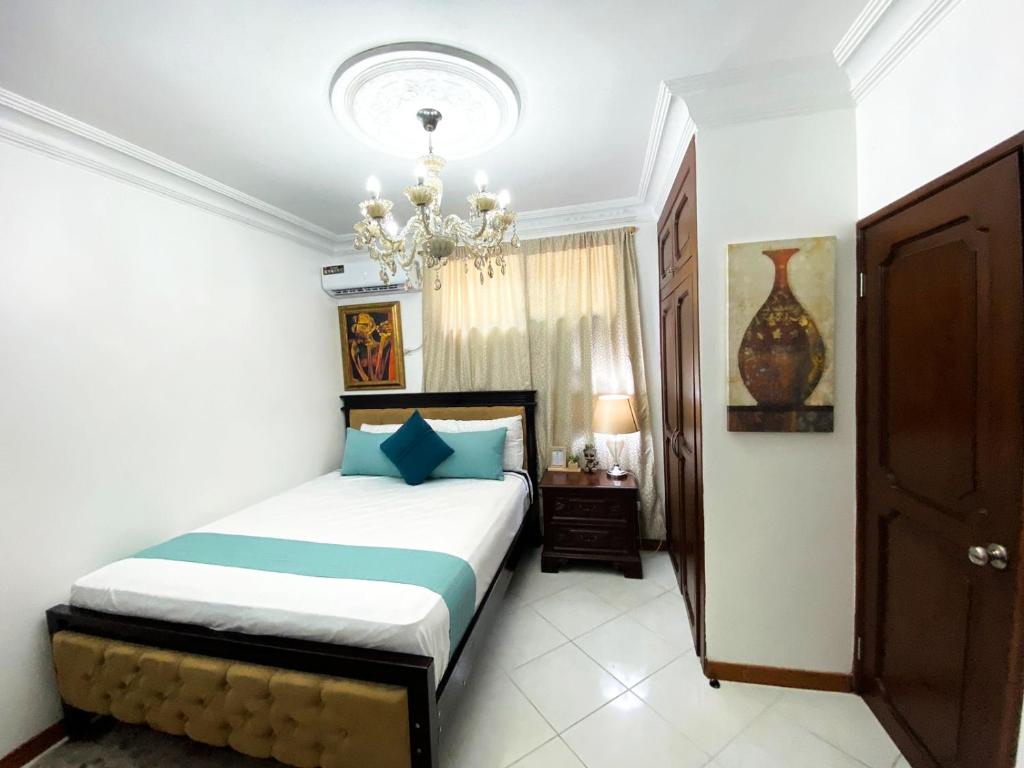 een slaapkamer met een bed en een kroonluchter bij Habitación a cinco minutos del aeropuerto y terminal terrestre in Guayaquil
