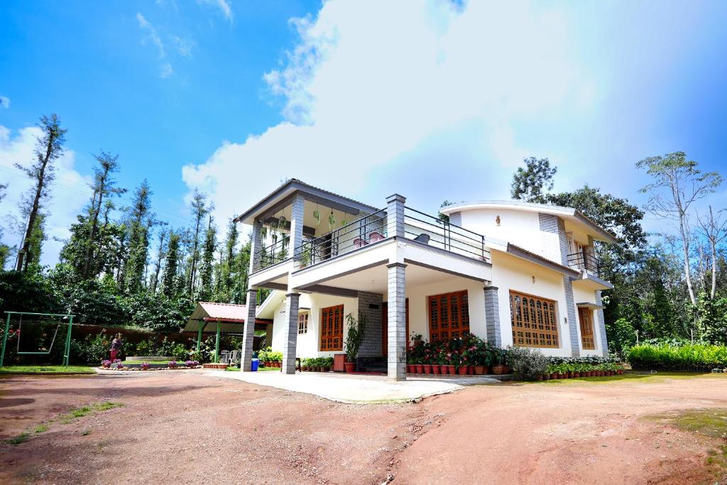 a white house with a balcony on top of it at Kodebailu Homestay - 3BH Full Villa, Home Food, Coffee Estate in Sakleshpur