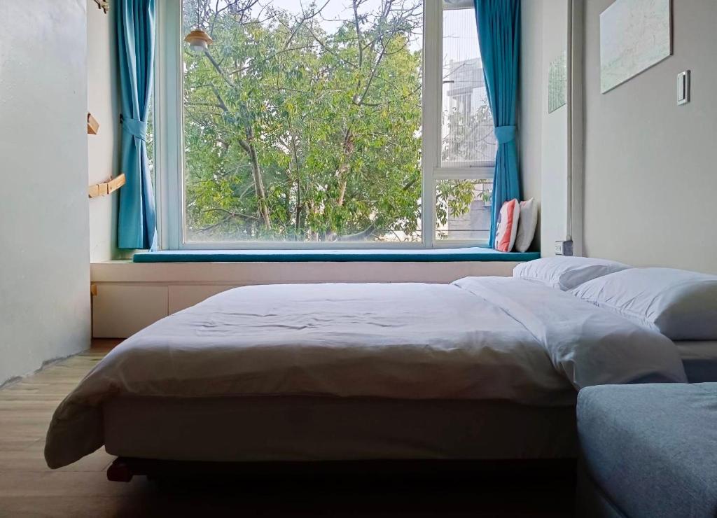 um quarto com 2 camas e uma janela com cortinas azuis em 東海小時光 Tong Hai Time Homestay em Longjing