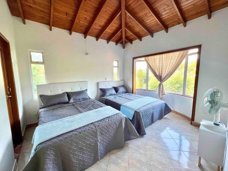 a bedroom with two beds and a large window at Charming villa near to Medellín Metro and malls in Copacabana