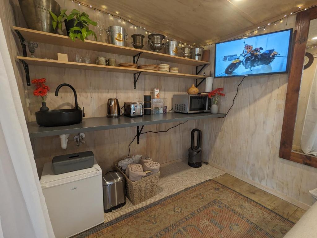 a kitchen with a tv on a wall at Piccola Casa Fiorita in Mount Maunganui