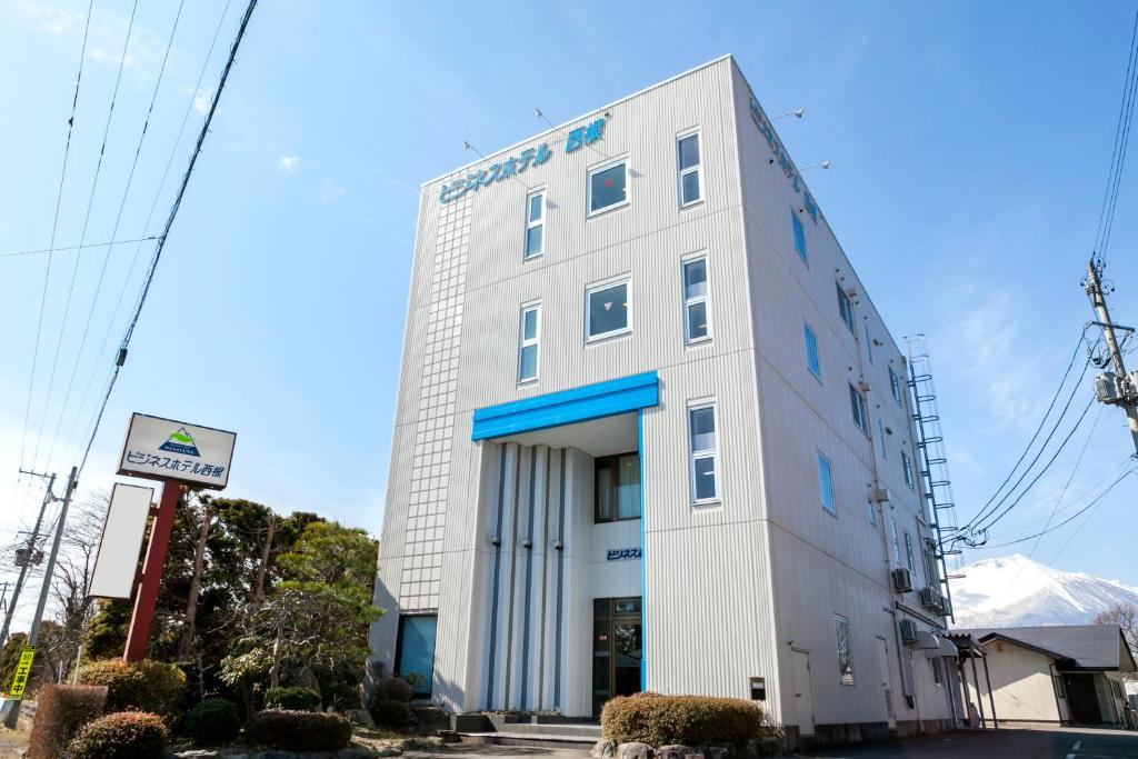 a white building with a sign in front of it at Business Hotel Nishine in Hachimantai