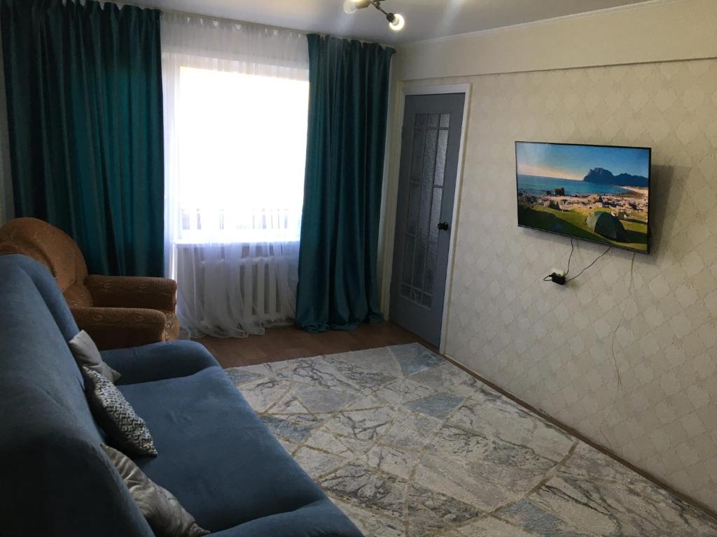 a living room with a blue couch and a window at LuxHome на УК in Ustʼ-Kamenogorsk