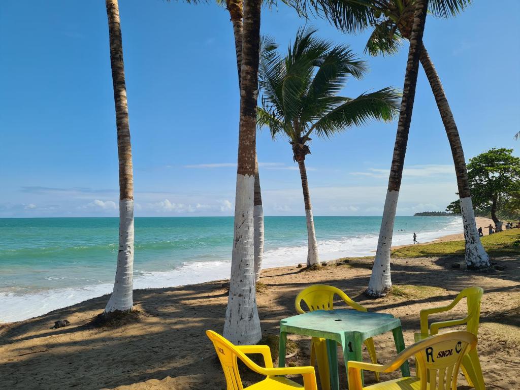 - une table et des chaises sur une plage bordée de palmiers dans l'établissement Casa com piscina na ilha de itaparica, à Vera Cruz de Itaparica