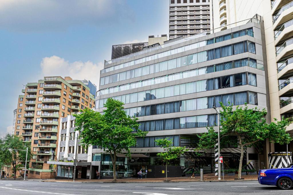 a blue car parked in front of a tall building at Song Hotel Sydney in Sydney