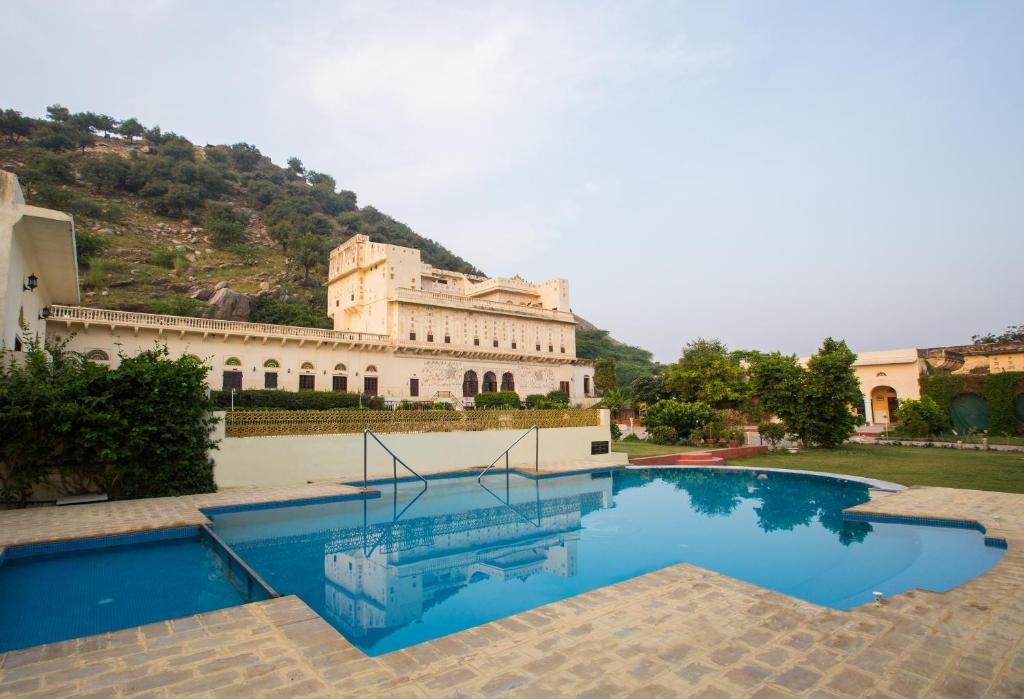a house with a swimming pool in front of a building at Castle Kalwar in Pachār