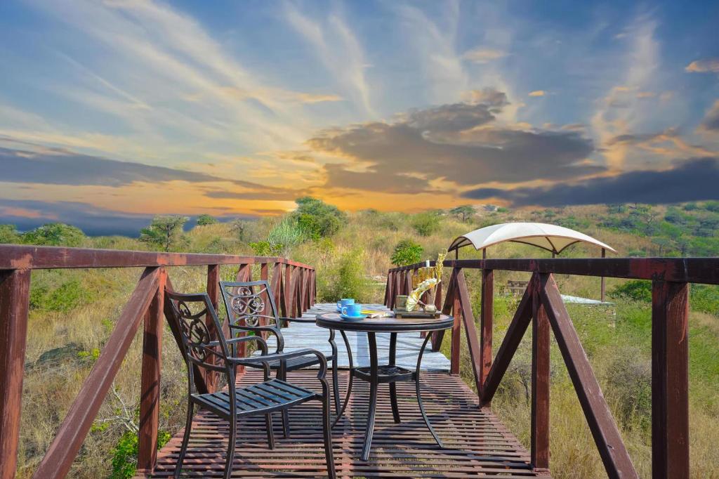 una mesa y 2 sillas en una terraza de madera en SaffronStays Moringa Valley Ashoka Villa, en Udaipur