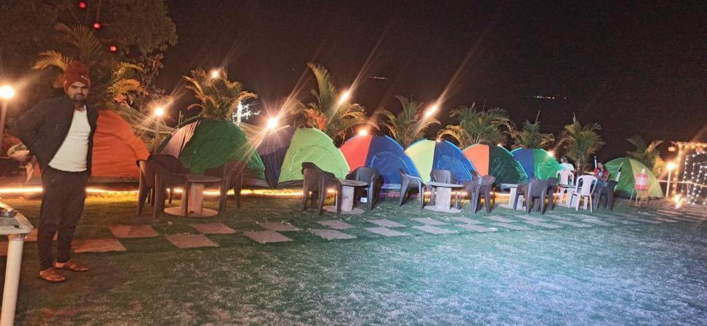 a man standing in front of a row of tables with umbrellas at LAKE FRONT CAMPING AND COTAGE in Lonavala