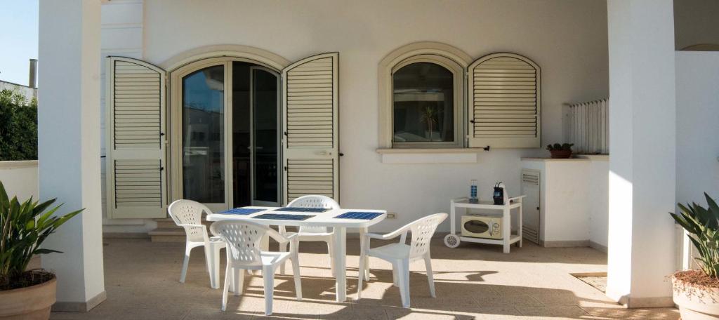 una mesa blanca y sillas en un patio en Le Bianche, en Torre Suda