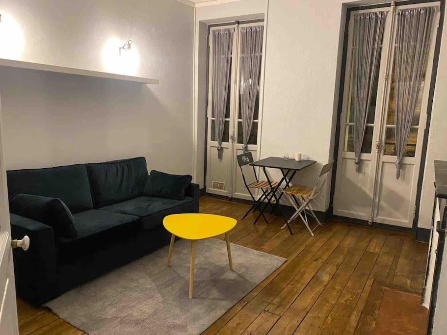 sala de estar con sofá negro y mesa amarilla en Appartement plein centre en Toulouse