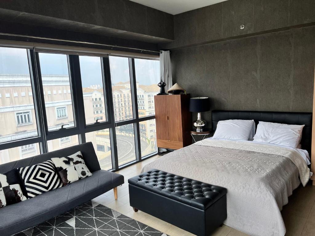 een slaapkamer met een bed, een bank en ramen bij Modern Studio at NAIA Terminal 3 in Manilla
