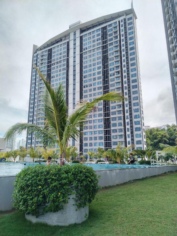 a large building with a palm tree in front of it at ArasTwo JQ Homestaykk LEVEL 22 SEAVIEW in Kota Kinabalu