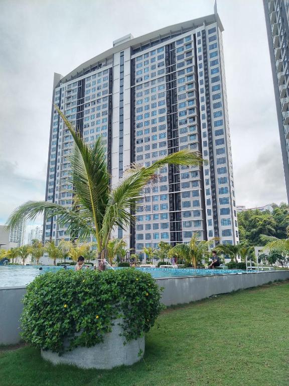 a large building with a palm tree in front of it at JQ ArasTwo Homestaykk LEVEL 22 SEAVIEW in Kota Kinabalu