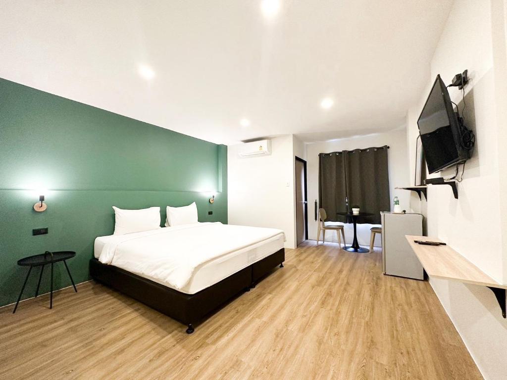 een slaapkamer met een bed en een groene muur bij NOW’S HOSTEL in Ban Chang