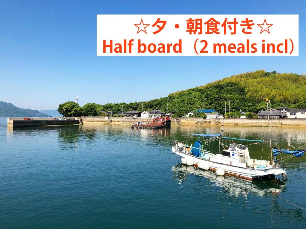 a small boat in a body of water at 離島-宿navelの学校-三原港から船で14分 in Mihara