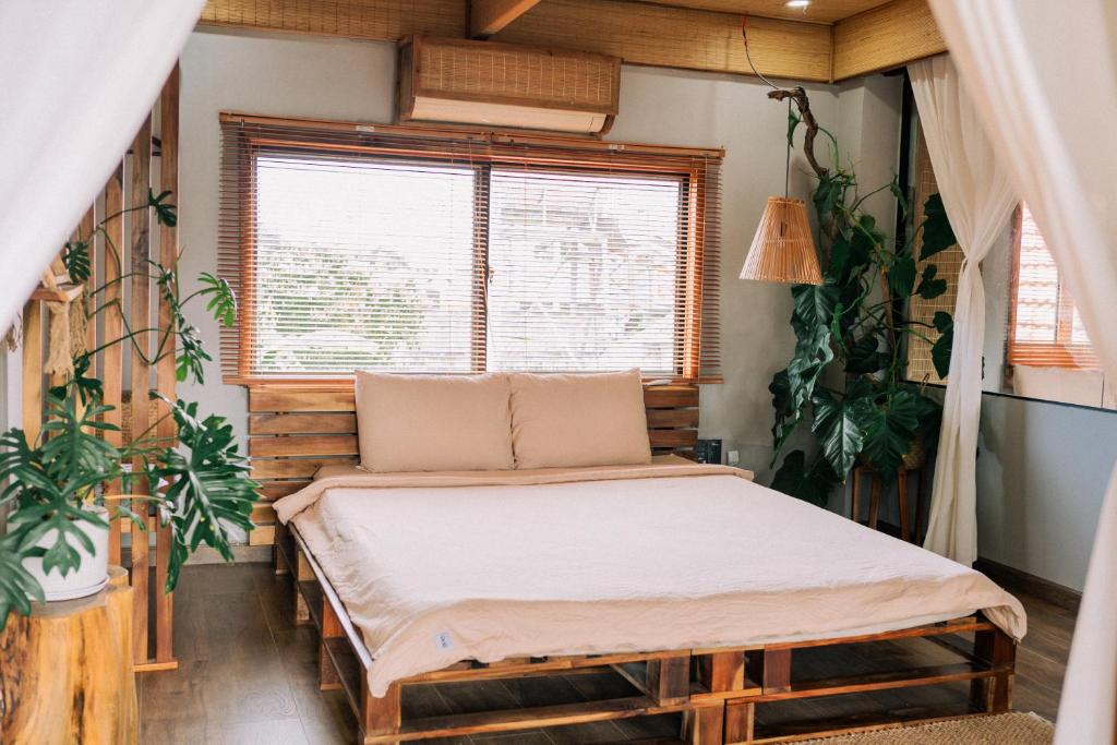 1 dormitorio con 1 cama en una habitación con plantas en TỊNH House Phú Quốc en Phu Quoc