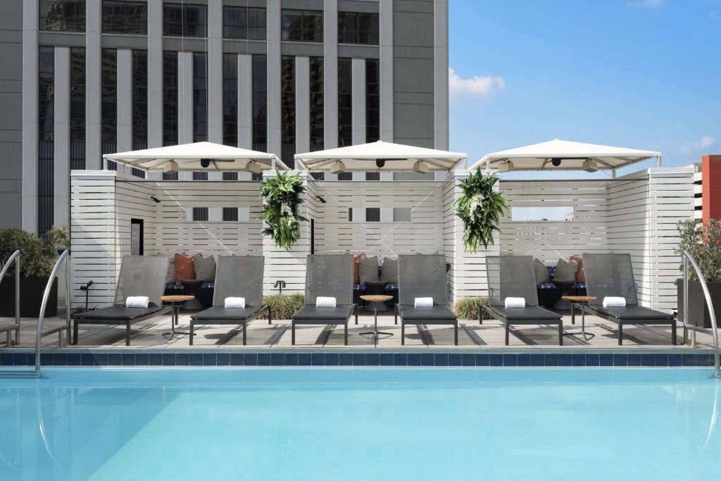 Una piscina con sillas y sombrillas al lado de un edificio. en Le Meridien New Orleans, en Nueva Orleans