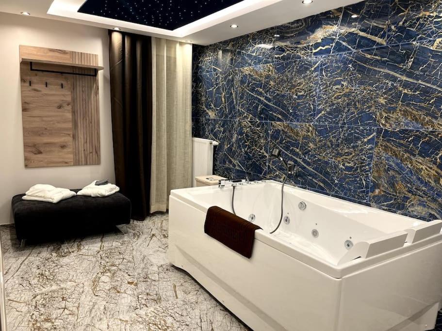 baño con bañera y pared de mármol en Appartement neuf haut standing - jacuzzi à Strasbourg, en Schiltigheim