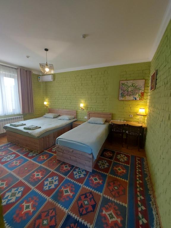 撒馬爾罕的住宿－MUSAVVIR，配有地毯的客房内的两张床