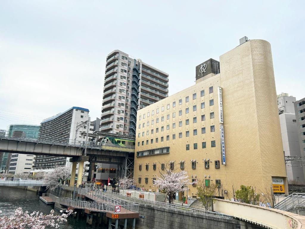 東京的住宿－Hotel Royal Oak Gotanda，一座高大的建筑,毗邻一条有建筑物的河流