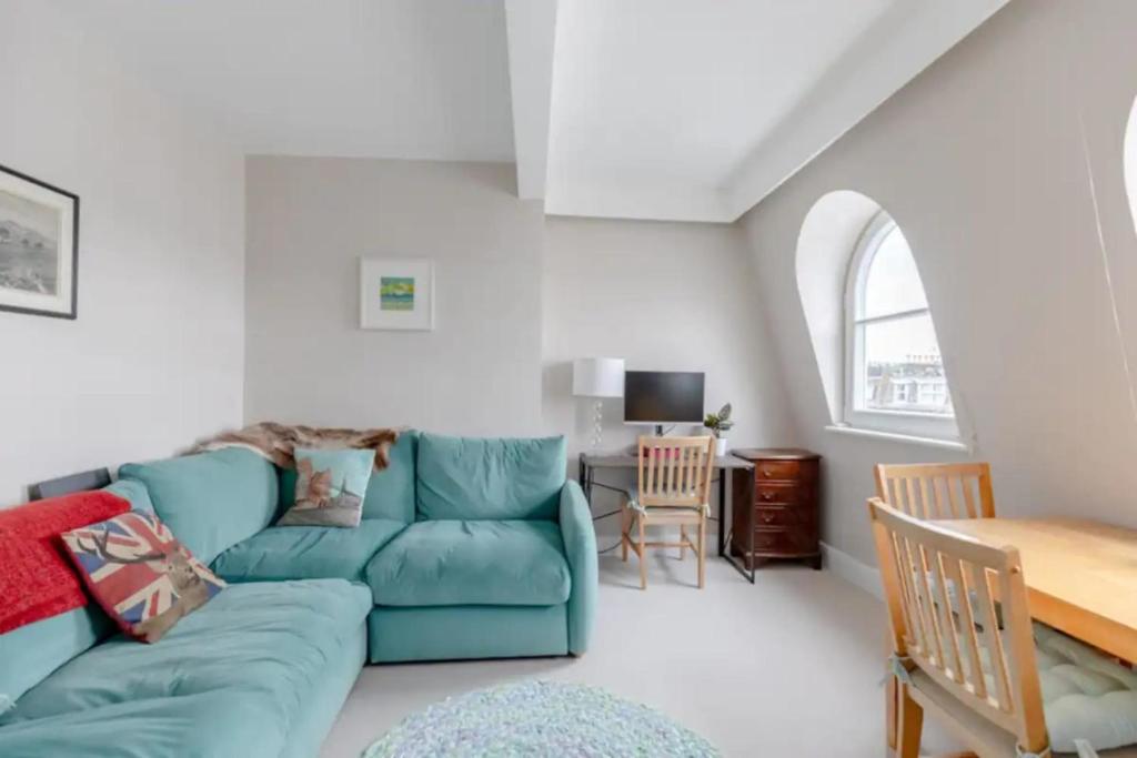 a living room with a blue couch and a table at Quaint & Cosy 1 Bedroom Flat - Kensington Olympia! in London